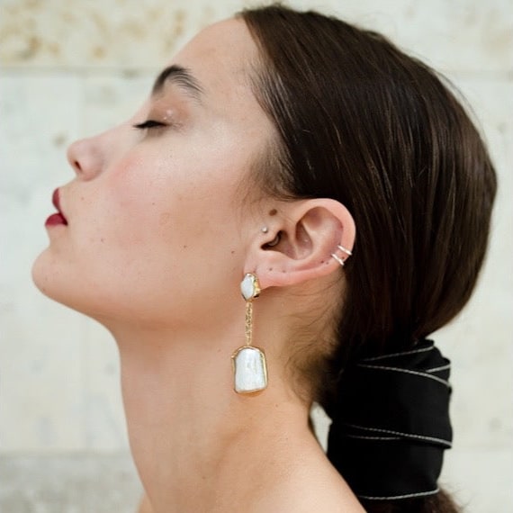Frame Baroques gold plated silver earrings on model.
